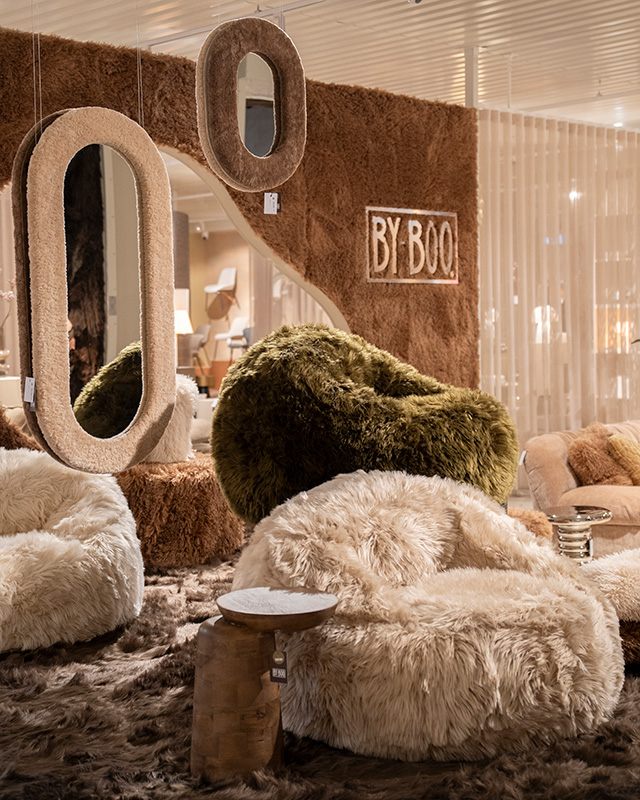 Podium bekleed met bruin bont, met daarop een beige en groene fluffy fauteuil.